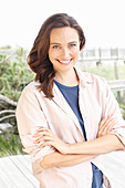 A young brunette woman wearing a blue t-shirt with a pale pink shirt blouse