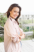 A young brunette woman wearing a pale pink shirt blouse