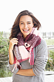 A young brunette woman wearing a grey woollen jumper and a thick scarf