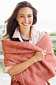 Junge brünette Frau in heller Hemdbluse mit lachsfarbener Stola aus Wolle