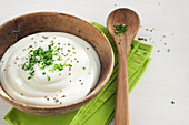 Yogurt quark with chives in a wooden bowl