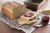 Fresh baked bread loaf, sliced and topped with butter and berry jam