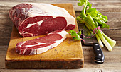 Beef entrecote, whole and sliced on a wooden board with a knife