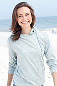 A young brunette woman wearing a light grey hooded top