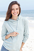 A young brunette woman wearing a light grey hooded top
