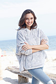 A young brunette woman wearing a light grey hoodie and jeans