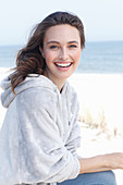 A young brunette woman wearing a light grey hoodie