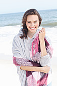 A young brunette woman wearing a light grey hoodie and a scarf