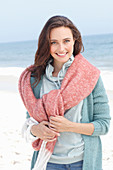 A young brunette woman wearing a hoodie, a cardigan and a woollen shawl