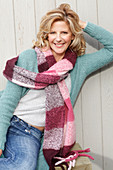 A blonde woman wearing a light jumper, a cardigan and a thick scarf
