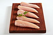 Raw chicken breast fillets on a wooden board