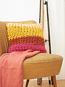 Multicoloured cushion made from knitted tubes made using knitting dolly