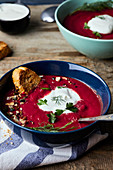 Bowl of Beetroot soup with coconut milk and sour cream, garnished with parsley and dill
