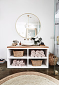 Vanity with counter basin, baskets and towels, round mirror on the wall