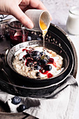 Drizzling honey on oatmeal with berries