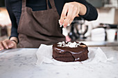 Sprinkling chocolate cake with coconut shavings