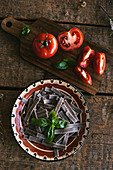 Buchweizennudeln auf Keramikteller daneben frische Tomaten