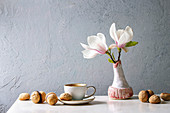 Baci di dama (Nussplätzchen, Italien) auf Tisch daneben Vase mit Magnolienblüten