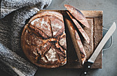 Flat-lay of freshly baked sourdough bread loaf and bread slices on rustic wooden board