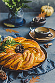 Autumn yeast cinnamon-pumpkin cake in a fancy wreath shape, coffee in the background