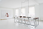 Folding chairs around long table in minimalist dining room with white floor