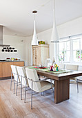 Chairs with white upholstery around dark dining table in modern kitchen-dining room