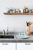 Shelf made from rustic wooden board above stone kitchen worksurface