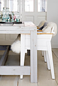 Sheepskin rugs on rustic chairs at pale grey wooden table