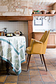 Yellow armchair in rustic kitchen-dining room with terracotta floor tiles