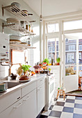 Weiße Küche mit Schachbrettfliesen und Balkontür