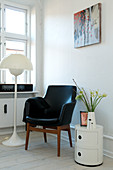 Black leather armchair next to floor lamp and order table