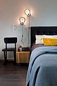 Doppelbett mit schwarzem Bettkopfteil und Wandleuchten im Schlafzimmer