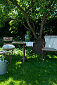 Sitzplatz mit alten Gartenmöbeln auf der Wiese im sommerlichen Garten