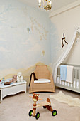 toddler bicycle in a baby room with wall mural and crib