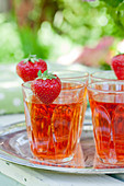Strawberries on rims of glasses of strawberry squash