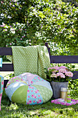 Round, pale blue and green patchwork cushion in garden