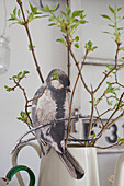 Aus Papier ausgeschnittenes Vogelbild an Zweigen in einer Kanne