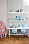 Two pale blue children's chairs at desk below two floating shelves