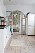Retro fridge, wooden floor and arched lattice door in white kitchen