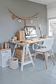 Desk and white chair below wall hanging made from wooden beads on grey wall of study