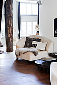 Corner easy chair and column made from tree trunk with bark in light-flooded living room