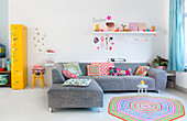 Grey sofa on white floor in living room with colourful accesories