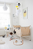 Child playing on floor next to vintage bed in bright bedroom