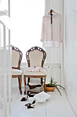 Antique upholstered chairs and ladies' clothing in bright room