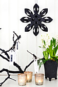 Black paper star on white wall, hyacinth and lanterns