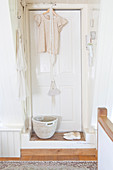 White door with a hanging blouse, basket, and shoes in front of it