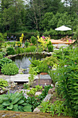 Idyllic garden pond with stone border, wooden walkways, and wooden sun deck
