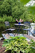 Gartentisch und -stühle auf Holzdeck am Teich