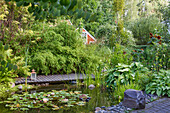 Idyllic garden pond with water lilies and a wooden footbridge