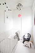 Crib, wooden horse and high chair with a rabbit stuffed animal in a white children's room
